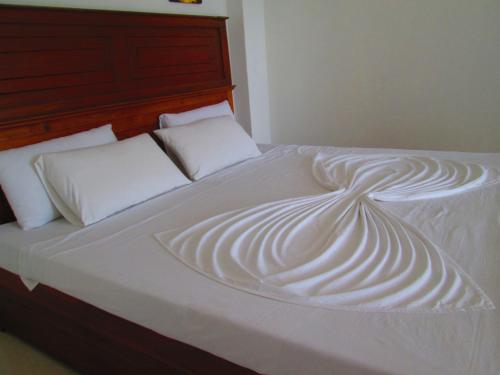 a large white bed with white sheets and pillows at Kandyan Sweet Villa in Kandy
