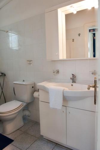 a white bathroom with a toilet and a sink at Karfas Bay View in Karfas