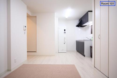 a room with white walls and a kitchen at Apartment Heights HANA in Sakai