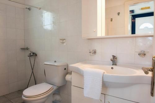 a white bathroom with a toilet and a sink at Karfas Bay View in Karfas