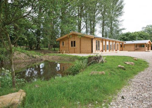 a wooden cabin with a pond in front of it at Peckmoor Farm Lodges in Misterton