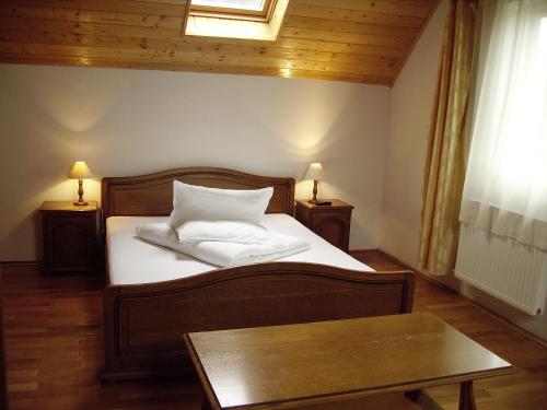 a bedroom with a bed with white sheets and a table at Vila Alisa in Bran