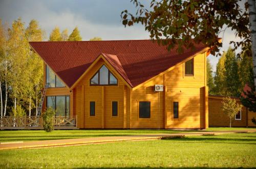 a large wooden house with a red roof at Woods Lake Resort in Potashëvo