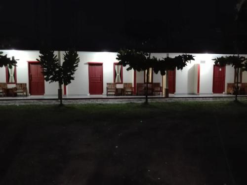 a white building with red doors and trees at night at Penginapan Karanglaut Sayangheulang in Cilauteureun