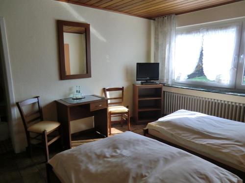 ein Hotelzimmer mit 2 Betten, einem Schreibtisch und einem TV in der Unterkunft Hotel-Restaurant Artemis in Willich