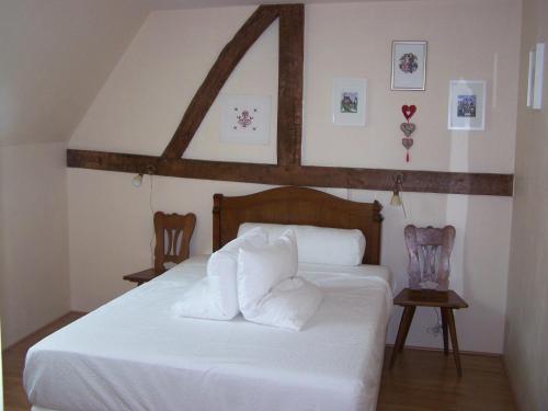 1 Schlafzimmer mit einem weißen Bett und 2 Stühlen in der Unterkunft GÎte rue de l'Ange in Hunspach