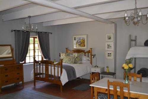 een slaapkamer met een bed en een tafel en stoelen bij Rooiheuwel Cottage in Wellington