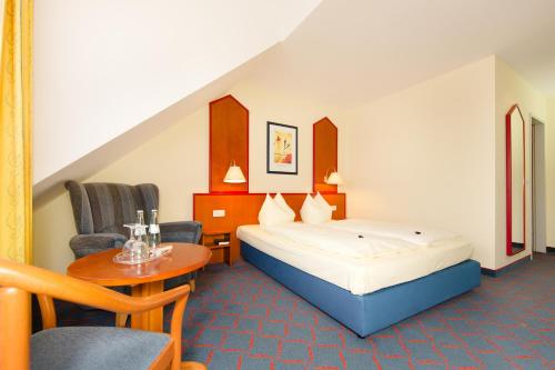 a hotel room with a bed and a table and chairs at Hotel Montana in Guxhagen