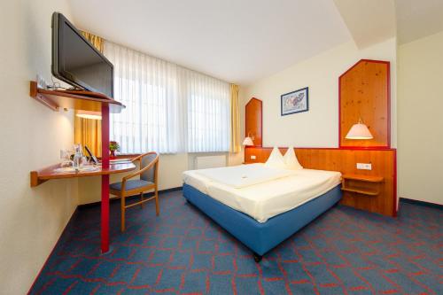 a hotel room with a bed and a desk and a television at Hotel Montana in Guxhagen