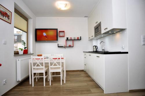 a kitchen with white cabinets and a table with chairs at Dream Apartment in Świnoujście