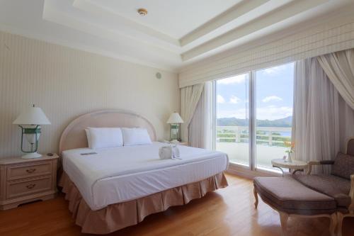 a bedroom with a large bed and a large window at Palasia Hotel in Koror