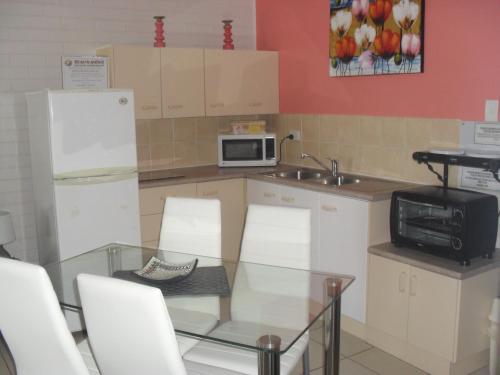 a kitchen with a glass table and a microwave at Beachlander Self-Contained Holiday Apartments in Coffs Harbour