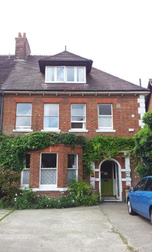 a red brick house with a blue car parked in front at Acorn Guest House in Oxford
