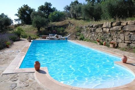 a large blue swimming pool next to a stone wall at Casa Lorenzo in Panicale
