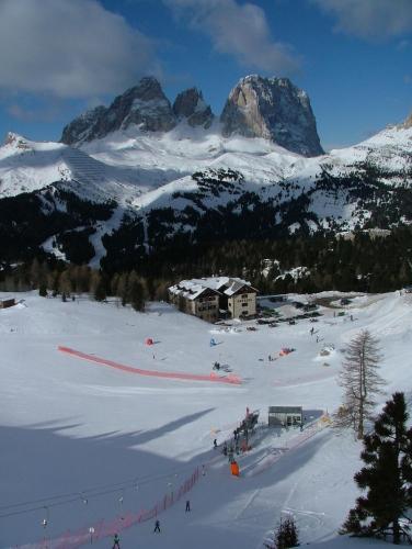 a ski lodge in the snow with mountains in the background at Hotel Garni Gonzaga in Canazei