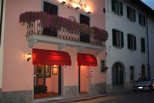 un edificio con sombrillas rojas y un balcón con flores en Locanda San Barnaba, en Scarperia