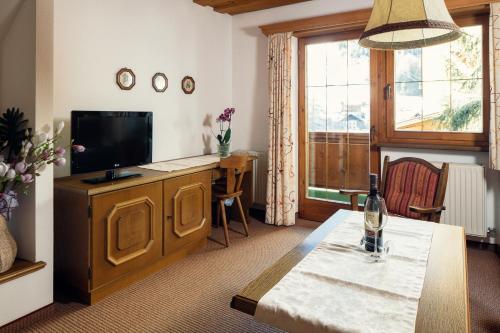 a living room with a television and a table with a bottle of wine at Haus am Mühlanger in Serfaus