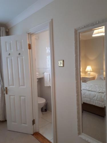 a bathroom with a mirror and a bedroom with a bed at Carrabaun House in Westport