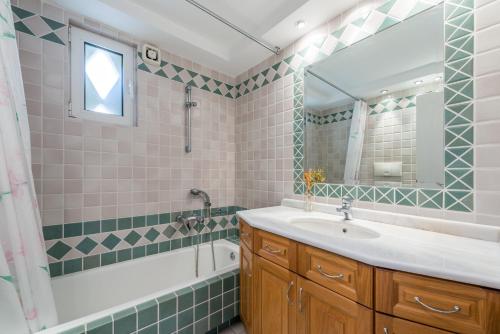 bagno con lavandino, vasca e specchio di Villa Adamite a Sounio
