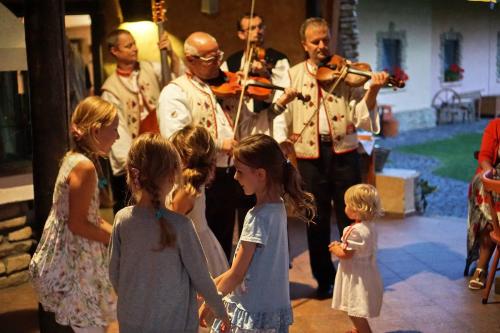 a group of children standing around a man playing violin at Penzion za mlynom in Bešeňová