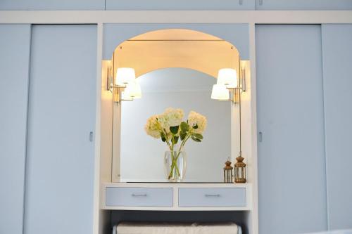 a dressing table with a mirror and a vase of flowers at Stowaway Beach House Camber Sands in Camber