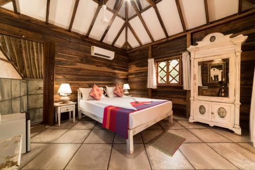 a bedroom with a bed in a wooden room at Little India Beach Cottages in Baga