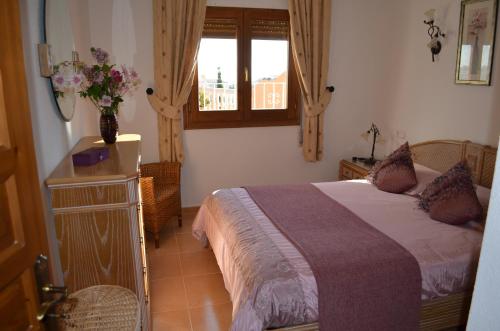 ein Schlafzimmer mit einem Bett und einem Fenster mit einer Vase aus Blumen in der Unterkunft Villa Magnolias in Benitatxell