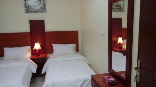 Habitación de hotel con 2 camas y espejo en Nice Suites & Hotels, en La Meca