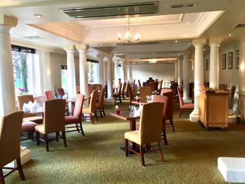 a dining room with tables and chairs and columns at Winchester Wessex Hotel by Sunday in Winchester