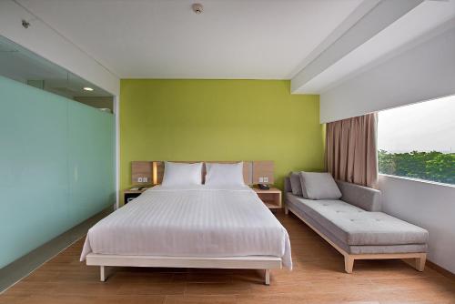 a bedroom with a bed and a couch and a window at Whiz Prime Hotel Pajajaran Bogor in Bogor