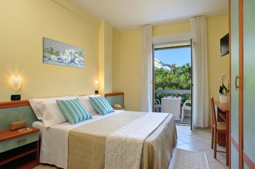 ミザーノ・アドリアーティコにあるHotel Riviera B&Bのベッドとバルコニー付きのホテルルーム