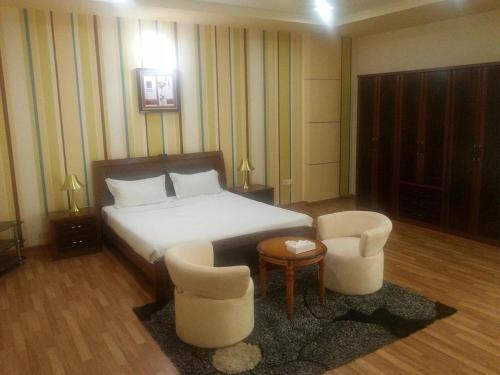 een slaapkamer met een bed en 2 stoelen en een tafel bij AL Sahab Tower in Manamah