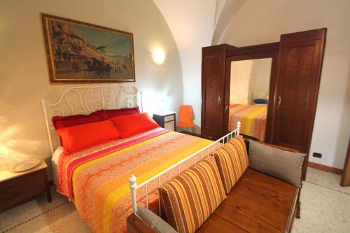 1 dormitorio con 1 cama con almohadas de color naranja y espejo en Corte di Pietra, en Ruffano