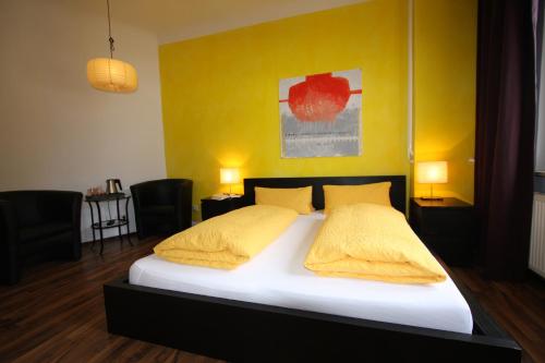 a bedroom with a large bed with yellow walls at Stadthotel Kleiner Berg in Friedrichshafen