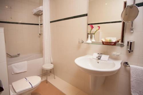 a white bathroom with a sink and a toilet at Hotel Otrada in Odesa