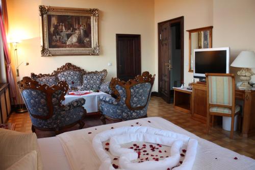a living room with chairs and a table and a television at Schlosshotel zum Markgrafen in Quedlinburg