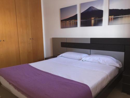 a bedroom with a large bed with three paintings on the wall at Apartamento Atlántico in Vecindario