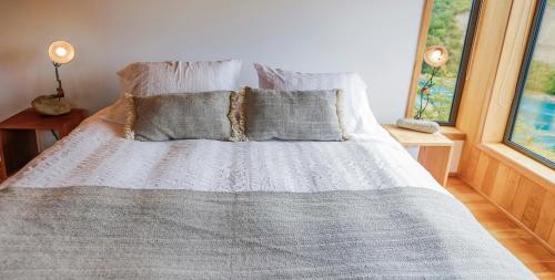 a bedroom with a bed with pillows and a window at Lodge BordeBaker in Puerto Bertrand