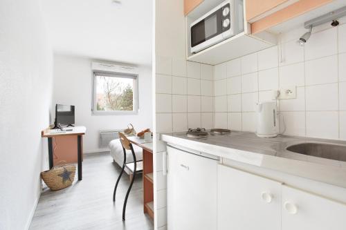a white kitchen with a sink and a microwave at Neoresid - R&eacute;sidence Clos Morlot in Dijon