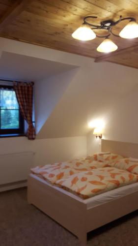 a bedroom with a bed with a wooden ceiling at Chata u Tří Sluk in Modrava