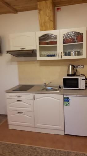 a kitchen with white cabinets and a sink and a microwave at Chata u Tří Sluk in Modrava