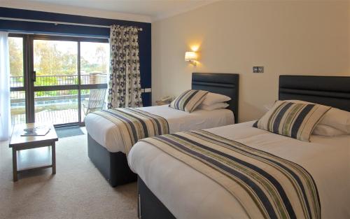 a hotel room with two beds and a balcony at Springfield Country Hotel, Leisure Club & Spa in Wareham