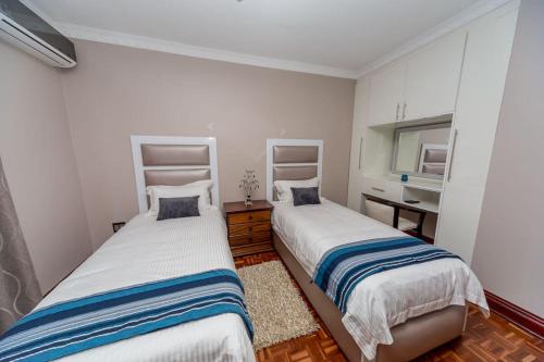 a bedroom with two beds and a sink in it at The Musafer Travel Lodge in Pietermaritzburg