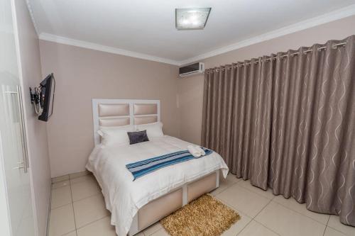 a bedroom with a bed and a window with curtains at The Musafer Travel Lodge in Pietermaritzburg
