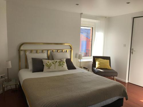 a bedroom with a large bed and a chair at Logis Hôtel O Lodge in Cleppé