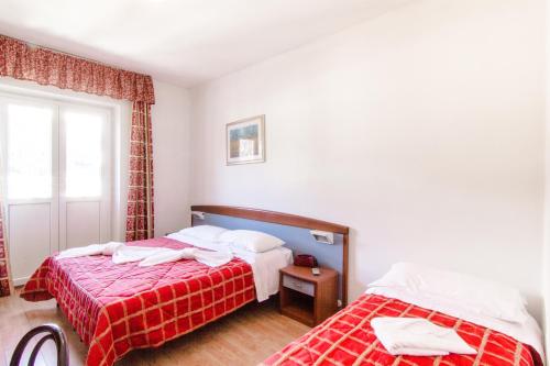 a bedroom with two beds and a window at Excelsior Hotel Cimone LowCost in San Martino di Castrozza