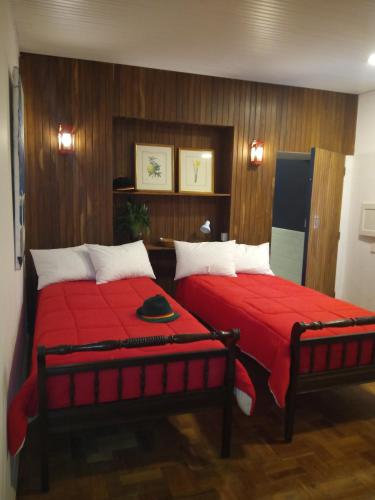a bedroom with two beds with a red blanket at Casa Piabanha - Centro Histórico in Petrópolis