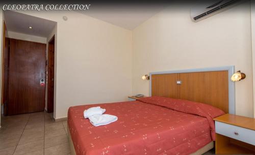a bedroom with a red bed with towels on it at Kris Mari in Kardamaina