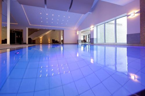 a large swimming pool with blue tiles on the floor at Romantik Hotel Waldschlösschen in Schleswig