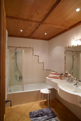a bathroom with a tub and a sink at Landhaus Alpensonne in Schattwald